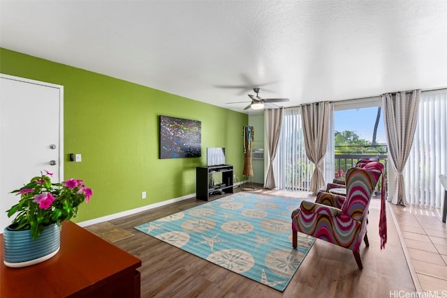 living room featuring ceiling fan, hardwood / wood-style flooring, and a textured ceiling