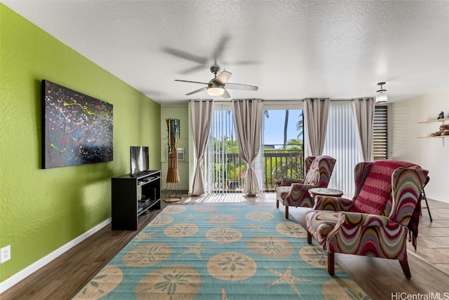 living area featuring ceiling fan, a textured ceiling, and dark hardwood / wood-style floors