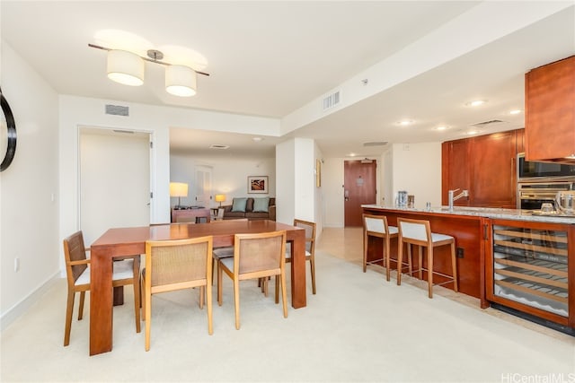 dining area with bar area, light colored carpet, and beverage cooler