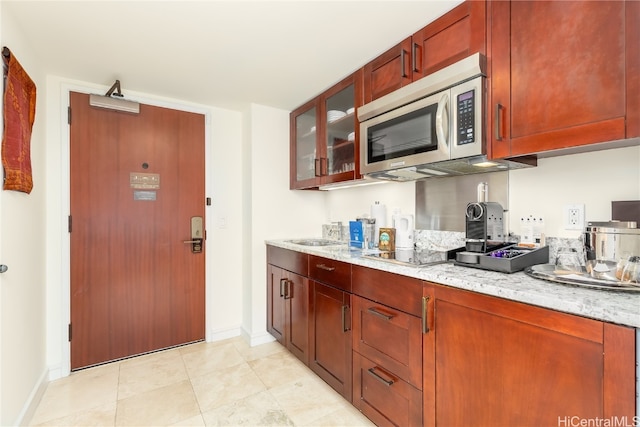 kitchen featuring light tile patterned flooring, light stone counters, cooktop, and sink