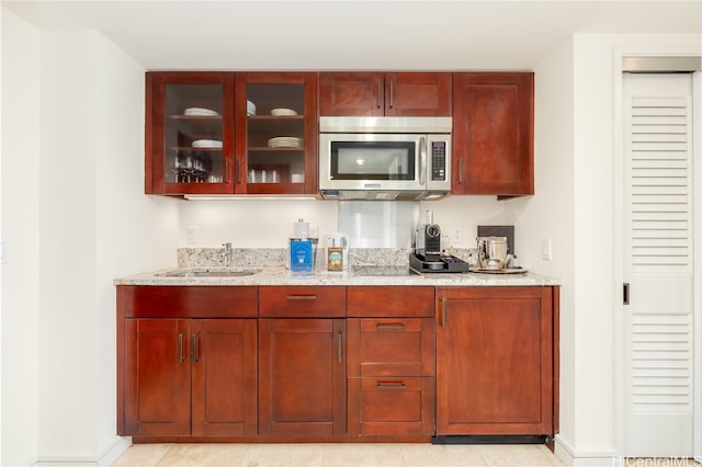 bar featuring sink, light stone countertops, and light tile patterned flooring