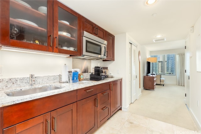 kitchen with sink, light stone countertops, and light carpet