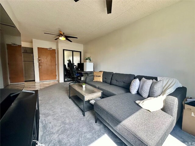 living area featuring light carpet, a textured ceiling, and a ceiling fan