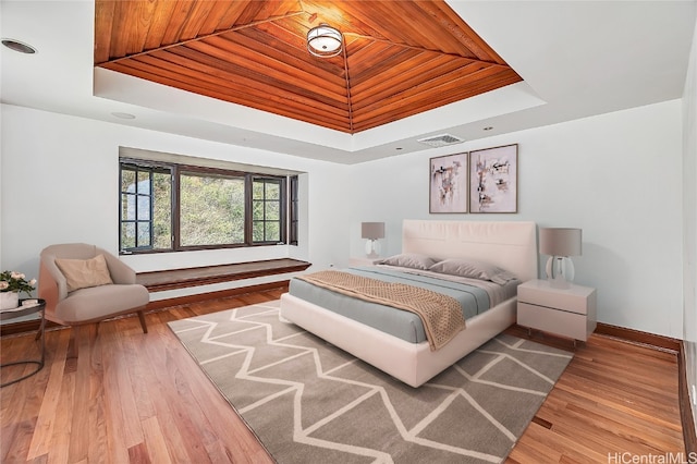 bedroom featuring a tray ceiling, wooden ceiling, and hardwood / wood-style flooring