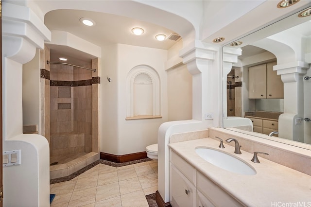 bathroom featuring toilet, vanity, and a tile shower