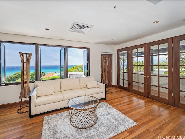 living room with a water view, wood-type flooring, and french doors