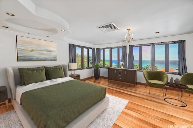 bedroom featuring a chandelier, wood-type flooring, and a water view