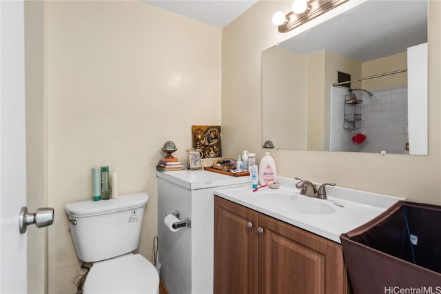 bathroom with vanity, tiled shower, and toilet