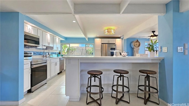 84-879 Moua St, Waianae, HI 96792 - kitchen with a kitchen bar, kitchen peninsula, beamed ceiling, stainless steel appliances, and white cabinets