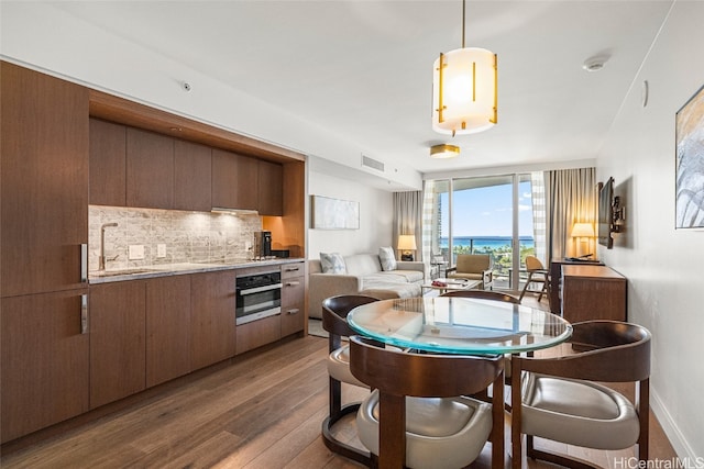 dining space featuring sink, a wall of windows, and dark hardwood / wood-style flooring