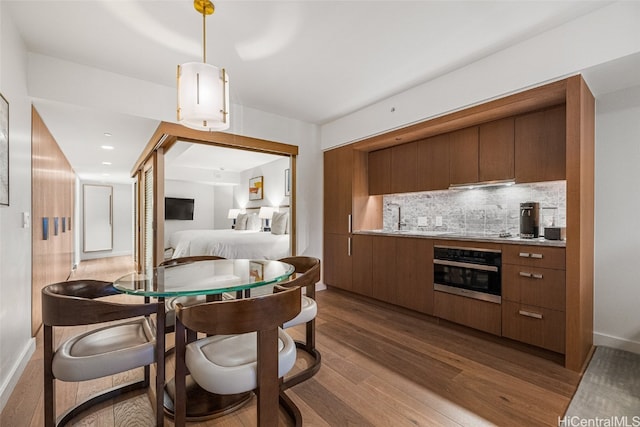 kitchen with decorative backsplash, stainless steel oven, dark hardwood / wood-style floors, black electric stovetop, and ventilation hood