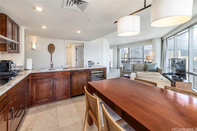 kitchen featuring wine cooler, black electric stovetop, light tile patterned flooring, and light stone counters