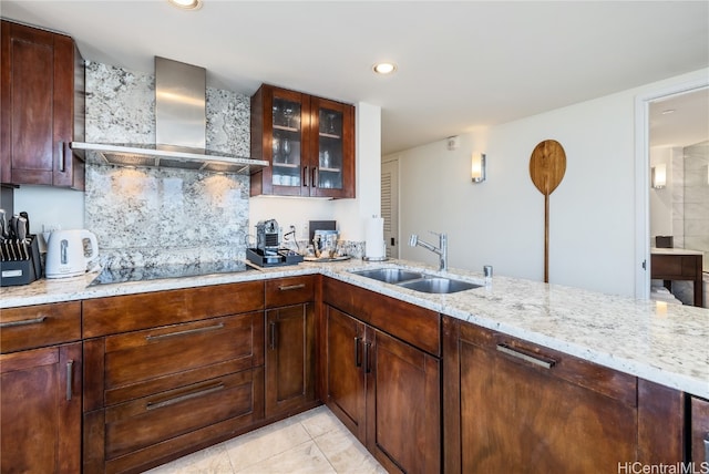 kitchen with black electric stovetop, wall chimney exhaust hood, sink, and light stone counters