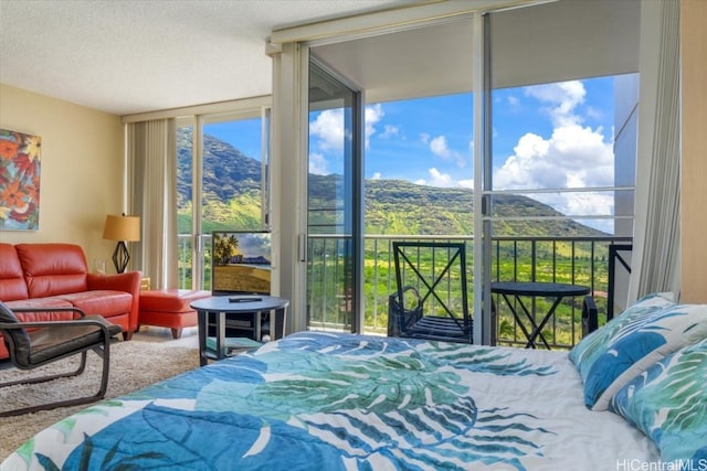 carpeted bedroom featuring multiple windows, a textured ceiling, and a wall of windows