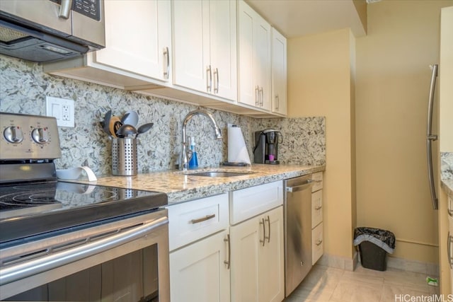 kitchen featuring decorative backsplash, sink, white cabinets, appliances with stainless steel finishes, and light stone counters