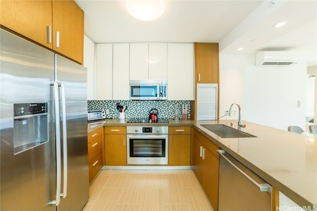 kitchen with appliances with stainless steel finishes, sink, an AC wall unit, white cabinetry, and decorative backsplash