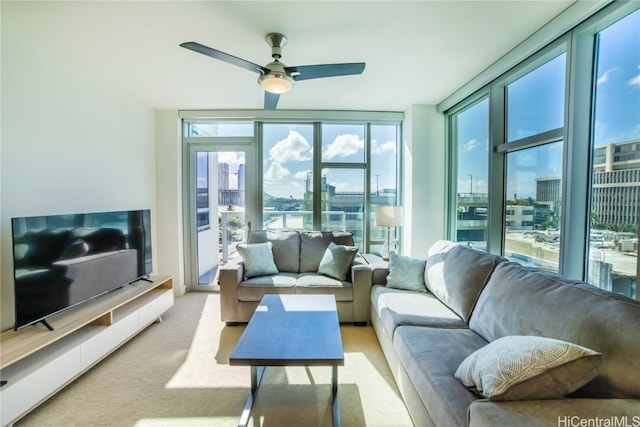 living room with a wealth of natural light, a wall of windows, light colored carpet, and ceiling fan