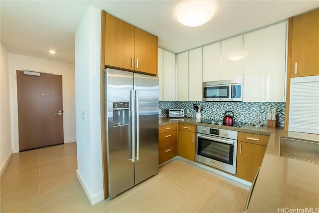 kitchen featuring decorative backsplash, white cabinets, and stainless steel appliances