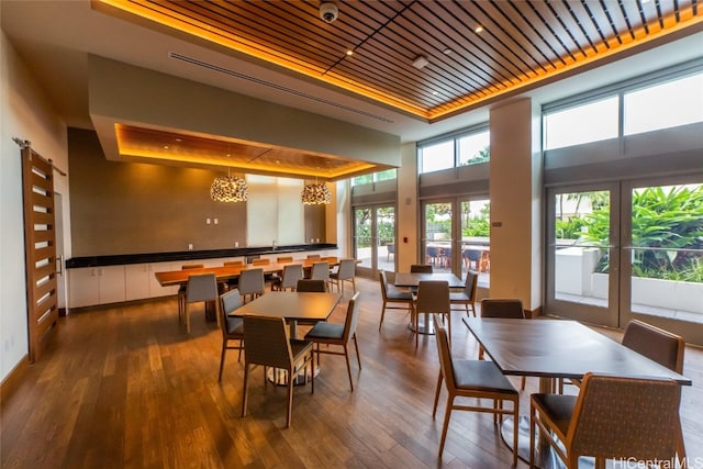 dining space featuring french doors, a barn door, wood-type flooring, and a raised ceiling