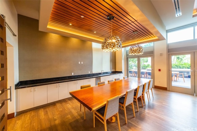 dining area with french doors, light hardwood / wood-style flooring, wood ceiling, and a tray ceiling