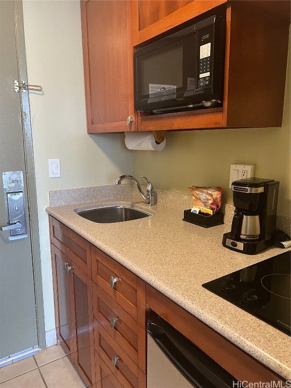 kitchen with black appliances, sink, light stone counters, and light tile patterned floors