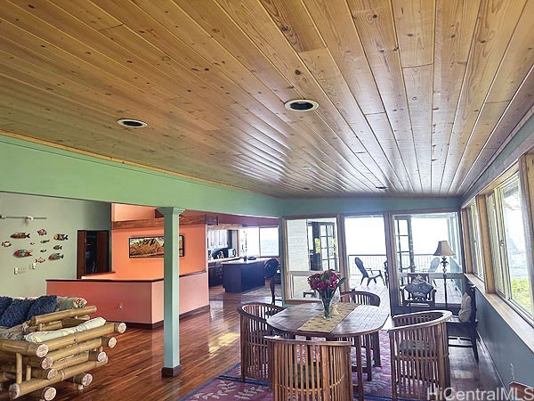 dining room with dark hardwood / wood-style flooring, vaulted ceiling, and wooden ceiling