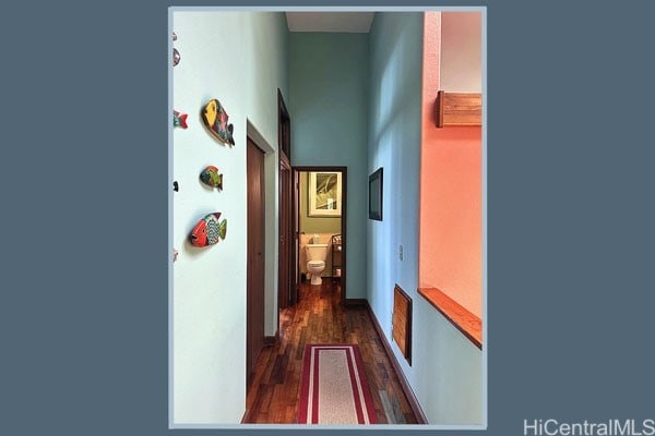 hall with a towering ceiling and dark hardwood / wood-style flooring