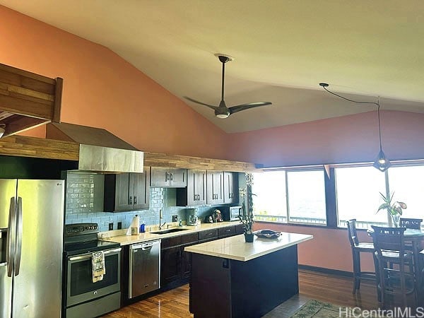 kitchen with hanging light fixtures, vaulted ceiling, a center island, appliances with stainless steel finishes, and dark hardwood / wood-style flooring