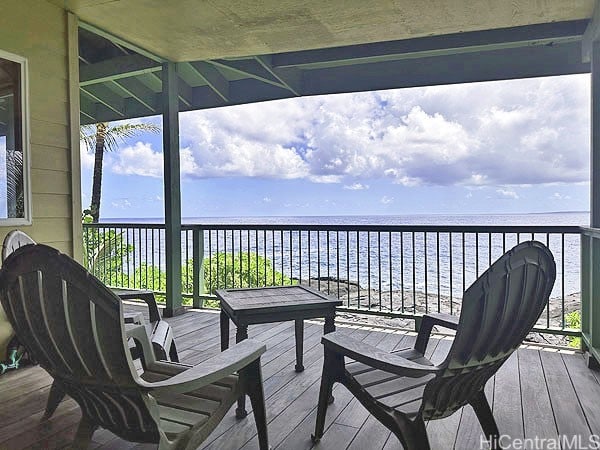 wooden terrace with a water view and a view of the beach