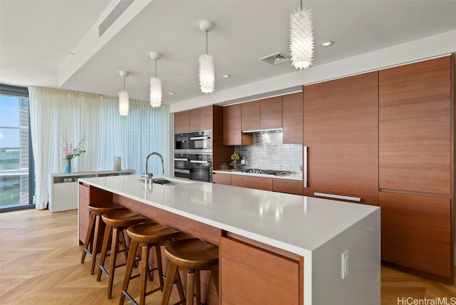 kitchen featuring visible vents, a sink, tasteful backsplash, appliances with stainless steel finishes, and light countertops