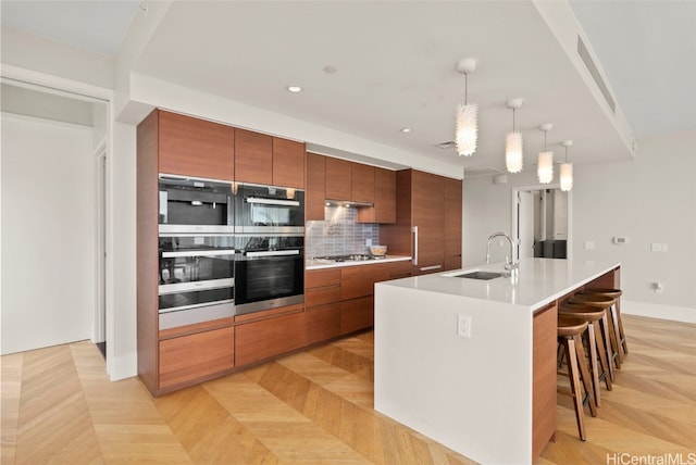 kitchen with backsplash, decorative light fixtures, brown cabinets, a kitchen breakfast bar, and a sink