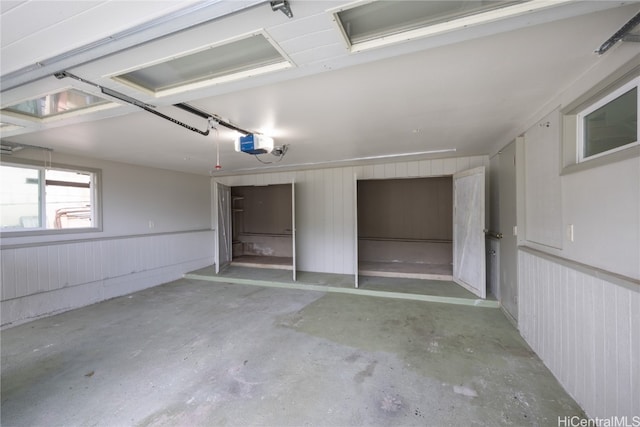 garage featuring a garage door opener and wooden walls