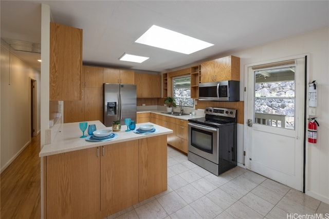 kitchen featuring light tile patterned floors, stainless steel appliances, a skylight, and sink