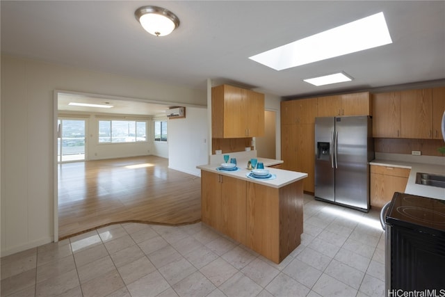 kitchen with a wall mounted air conditioner, light wood-type flooring, kitchen peninsula, stove, and stainless steel fridge with ice dispenser