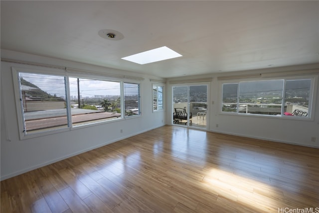 spare room with light hardwood / wood-style floors and a skylight