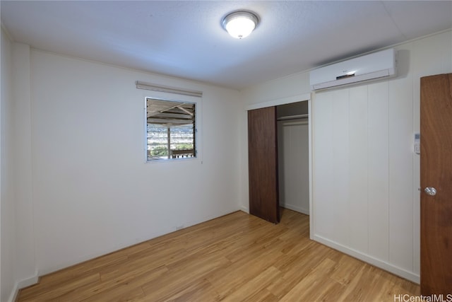 unfurnished bedroom featuring light hardwood / wood-style flooring, a wall mounted air conditioner, and a closet