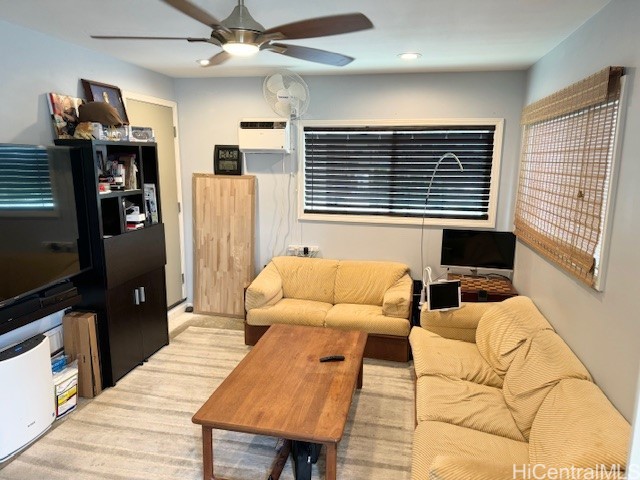 living room with ceiling fan and a wall unit AC