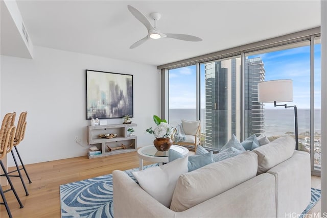 living room with hardwood / wood-style floors, a water view, floor to ceiling windows, and ceiling fan