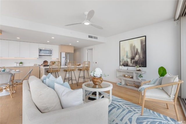 living room with ceiling fan and light hardwood / wood-style flooring