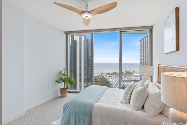 carpeted bedroom featuring a water view and ceiling fan