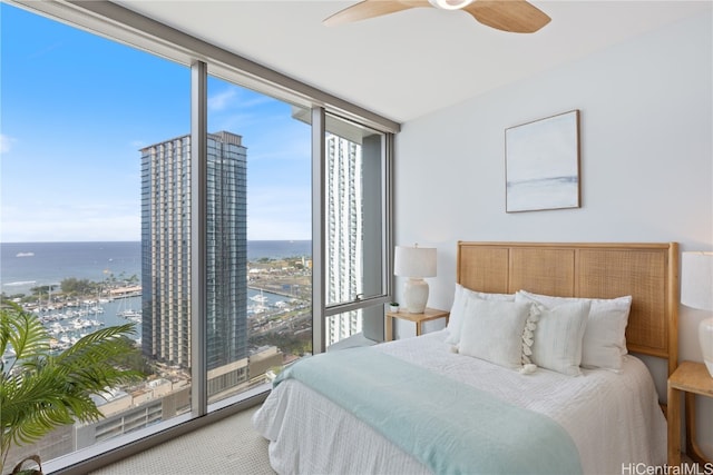 carpeted bedroom featuring ceiling fan and a water view