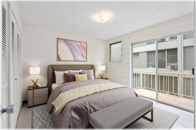 bedroom featuring access to outside, a textured ceiling, a closet, and wooden walls