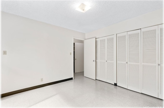 unfurnished bedroom with a textured ceiling and multiple closets