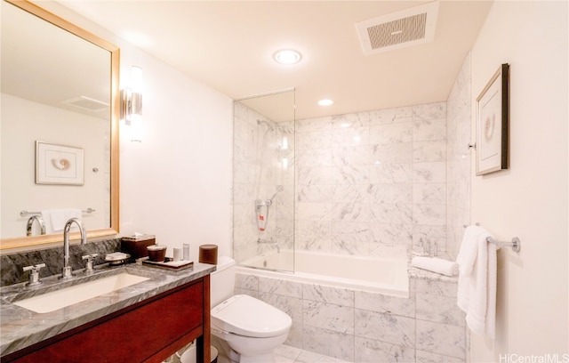 full bathroom with tiled shower / bath, vanity, and toilet