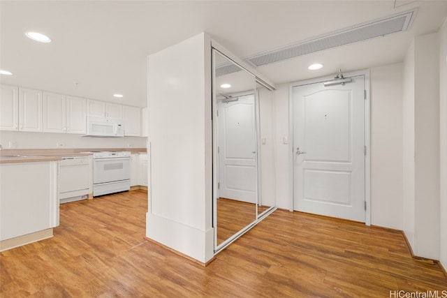 kitchen with light wood-type flooring, white appliances, white cabinetry, and sink