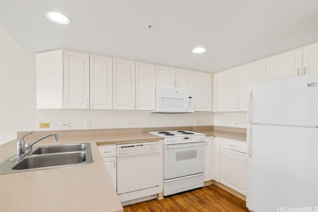 kitchen with sink, white cabinets, wood-type flooring, and white appliances