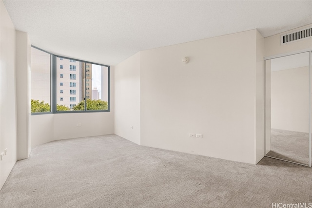 empty room featuring a textured ceiling and light carpet