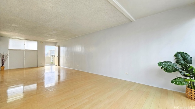 empty room with a textured ceiling and light hardwood / wood-style floors