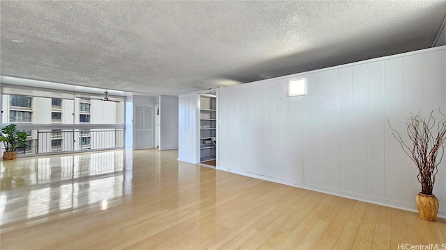 spare room with a textured ceiling, light wood-type flooring, and ceiling fan