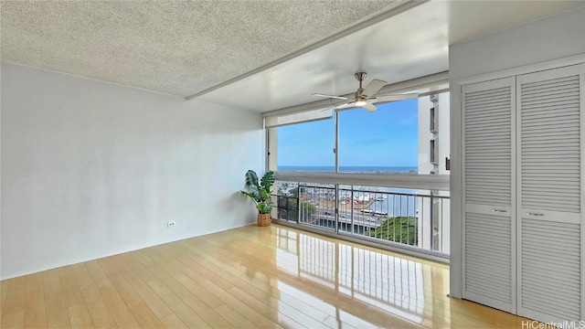 interior space featuring a textured ceiling, a water view, light wood-type flooring, and expansive windows